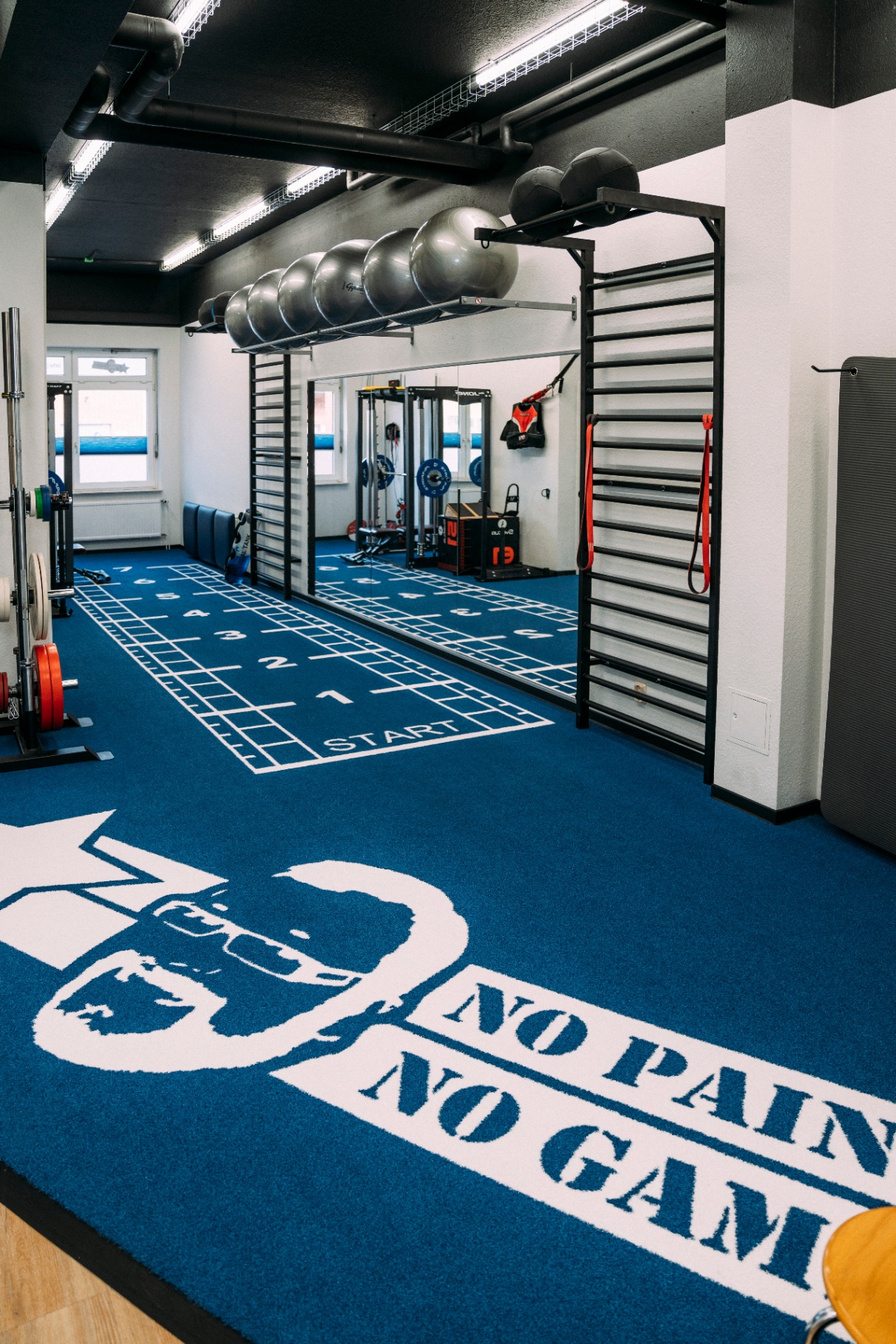 Trainingsraum mit No Pain No Game Logo-Teppich